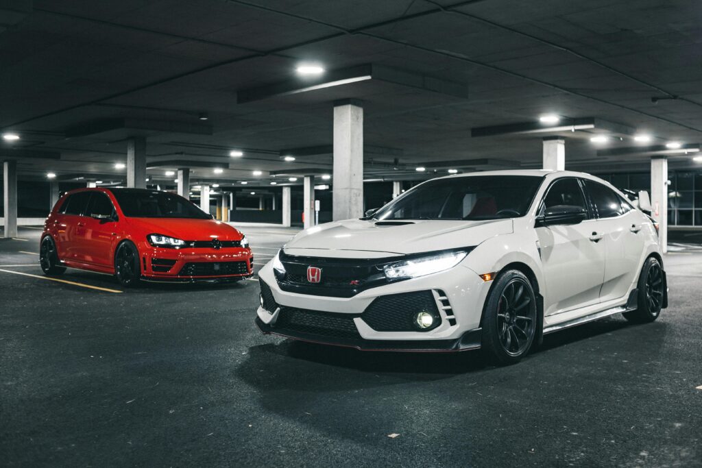 Two sleek sports cars parked in a dimly lit underground garage, showcasing contemporary automotive design.